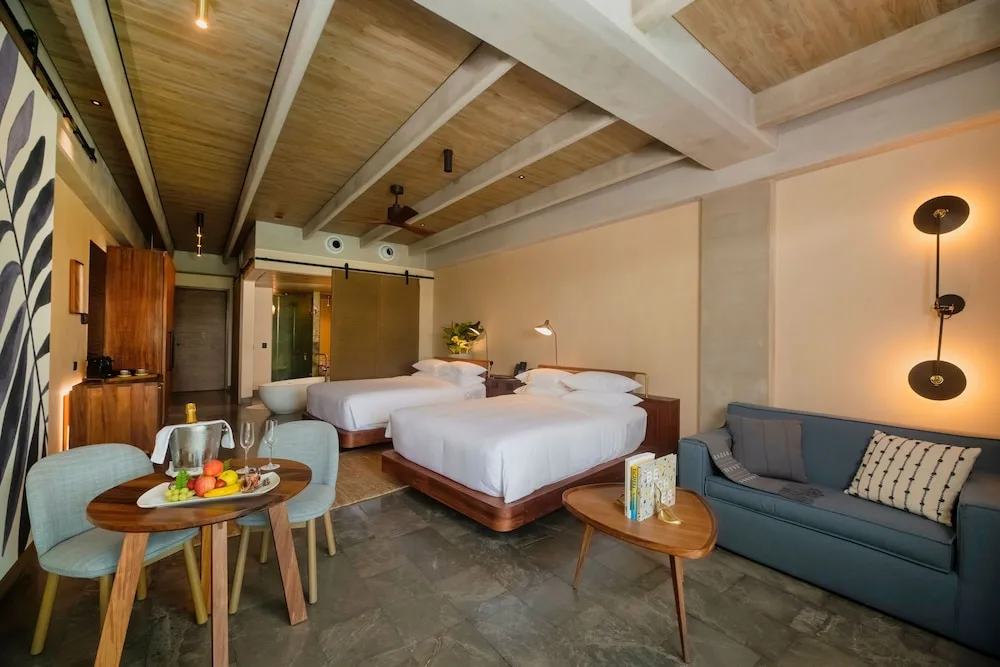 Junior Suite with two beds, sofa, dining table, and soaking tub at Atelier Playa Mujeres.