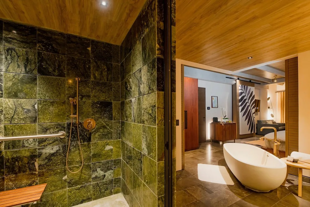 Accessible suite shower with grab bars and freestanding tub at Atelier Playa Mujeres.