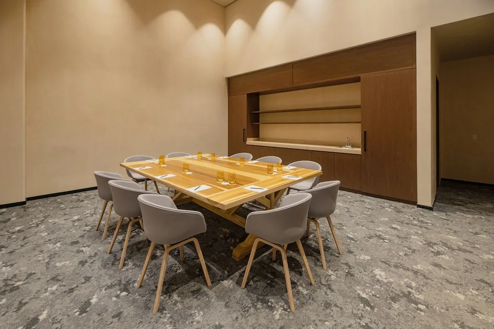 Small meeting room with a wooden table and gray chairs at Atelier Playa Mujeres.
