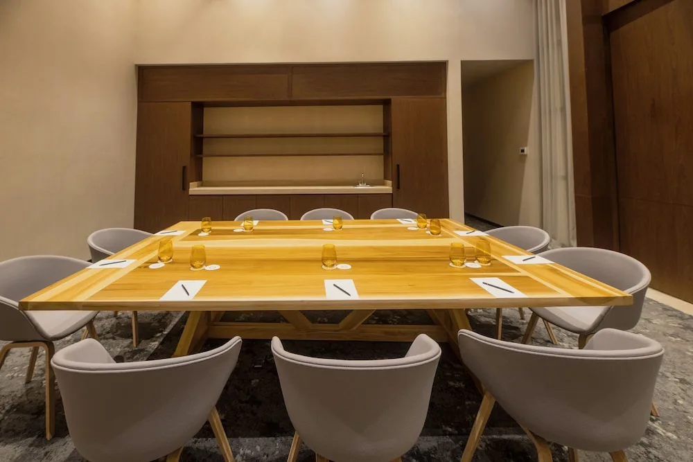 Close view of a wooden meeting table set with glasses at Atelier Playa Mujeres.