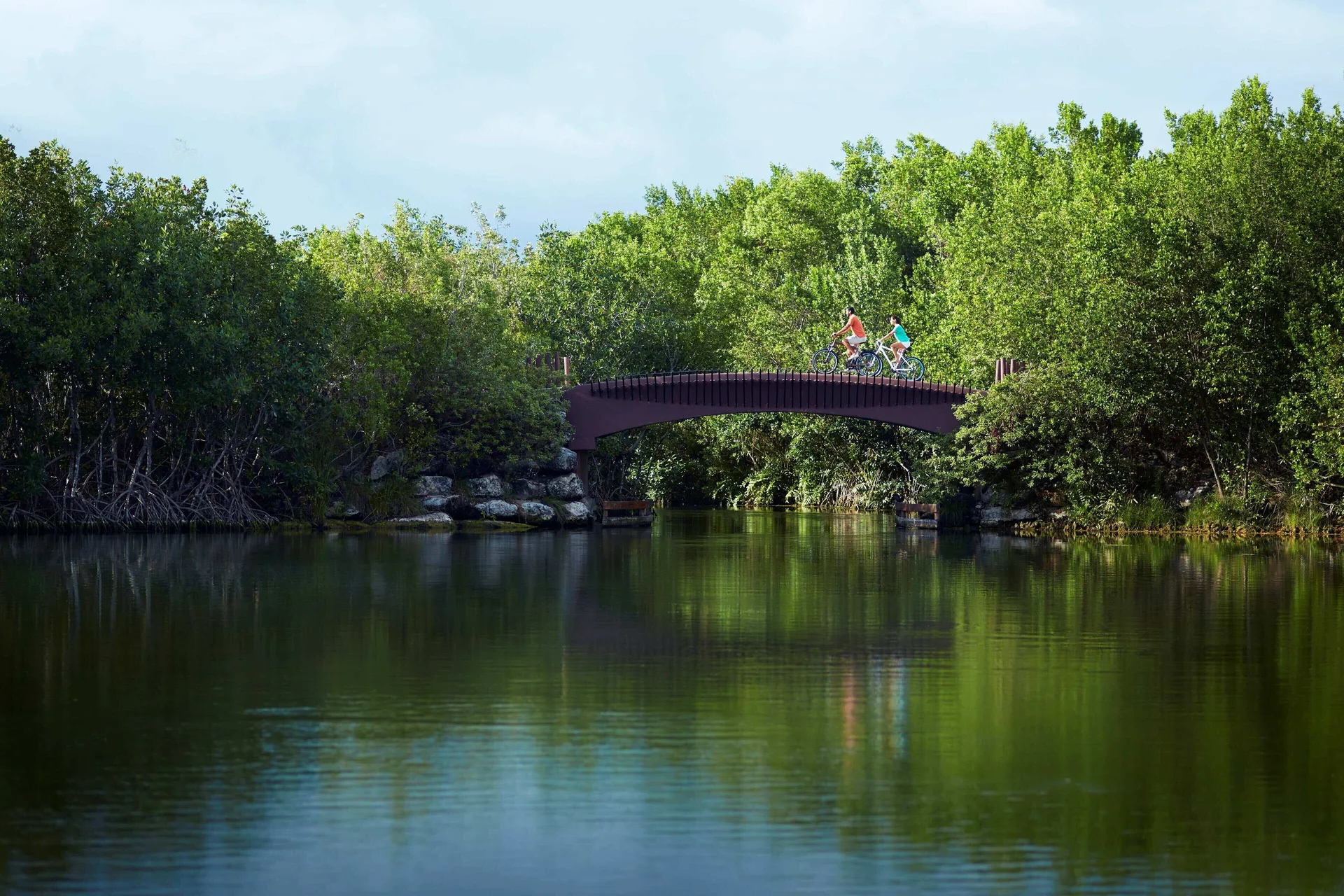 Two cyclists ride across a bridge over a lagoon at Banyan Tree Mayakoba.