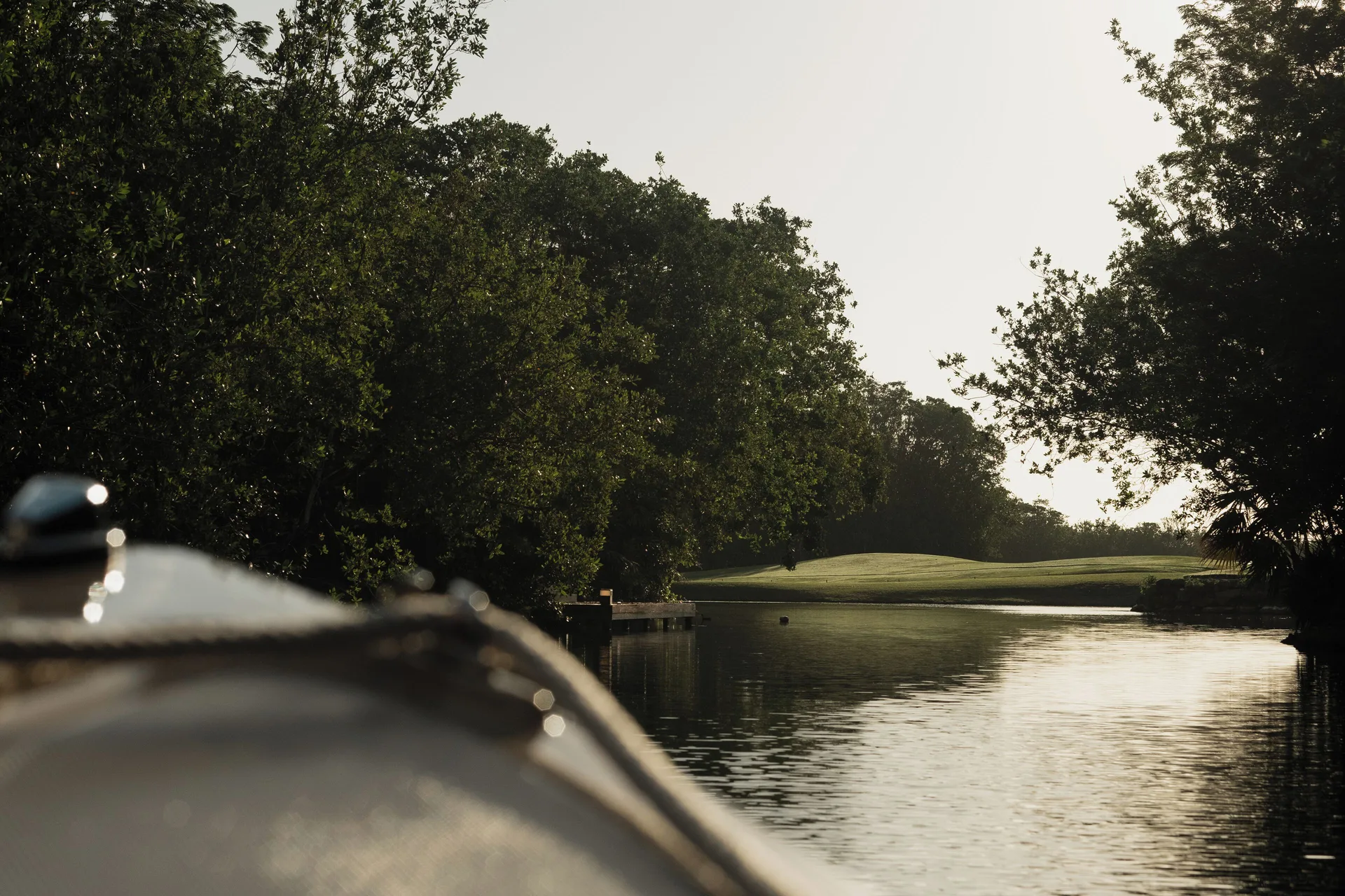 Lagoon waterway bordered by trees and golf greens at Banyan Tree Mayakoba.