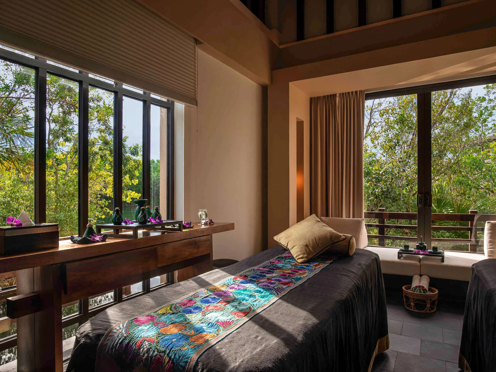 Spa treatment room with massage tables and treetop windows at Banyan Tree Mayakoba.