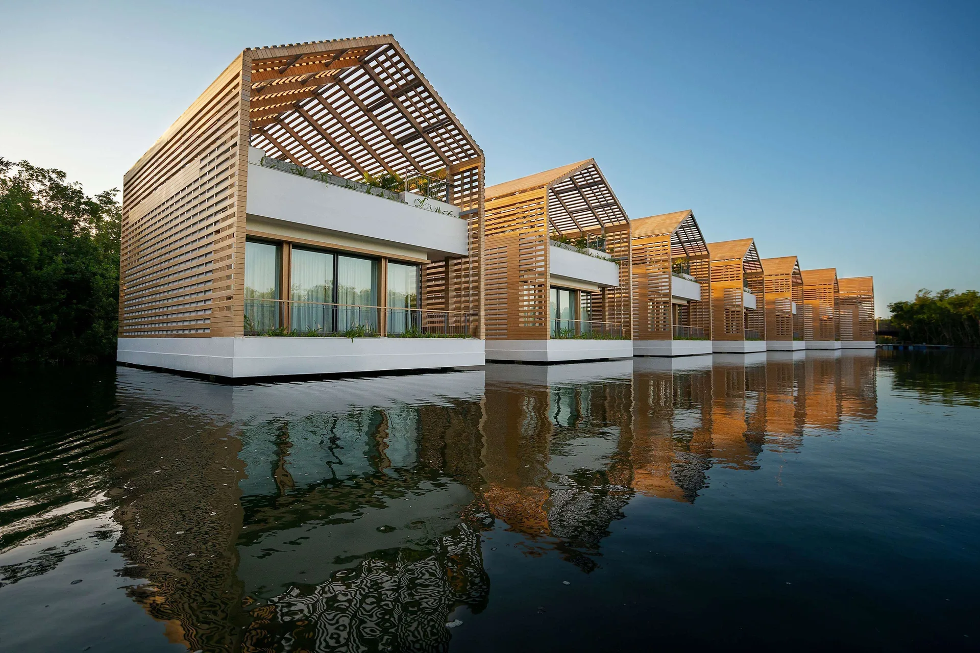 Lagoon & Sunset Rooftop Pool Villa exteriors reflected on the water at Banyan Tree Mayakoba.
