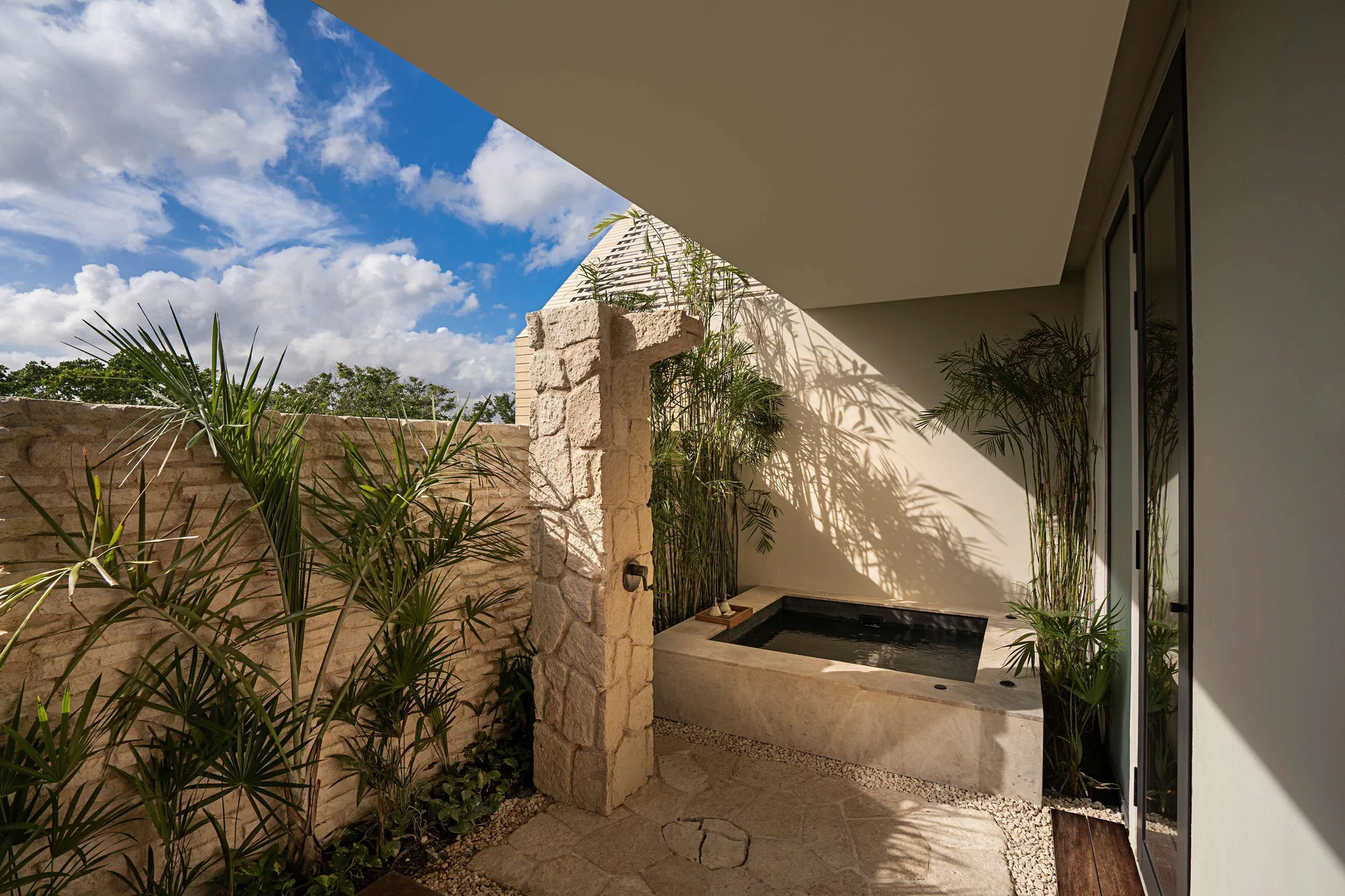 Oceanfront Veranda Pool Suite outdoor bath courtyard with stone walls at Banyan Tree Mayakoba.