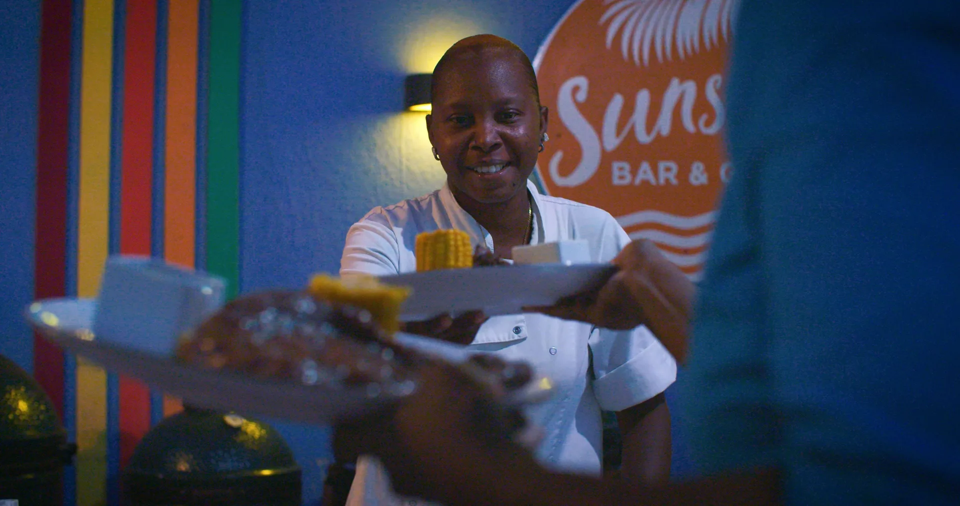 Staff member serving plated food at a bar at Blue Bay Curacao Golf & Beach Resort.