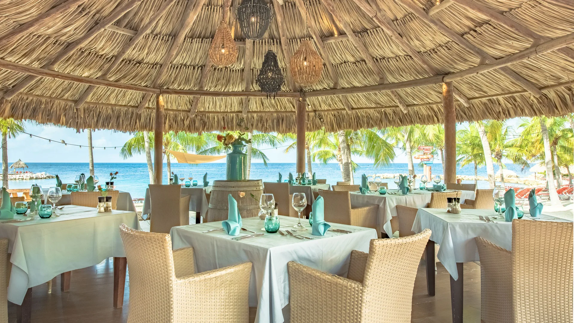 Beachfront dining under a thatched roof at Blue Bay Curacao Golf & Beach Resort.
