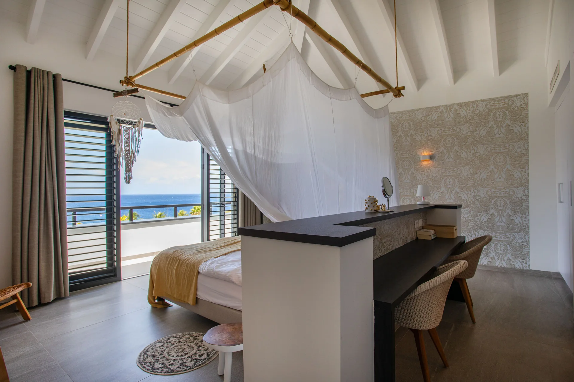 Canopy bed and ocean-facing balcony in the penthouse at Blue Bay Curacao Golf & Beach Resort.