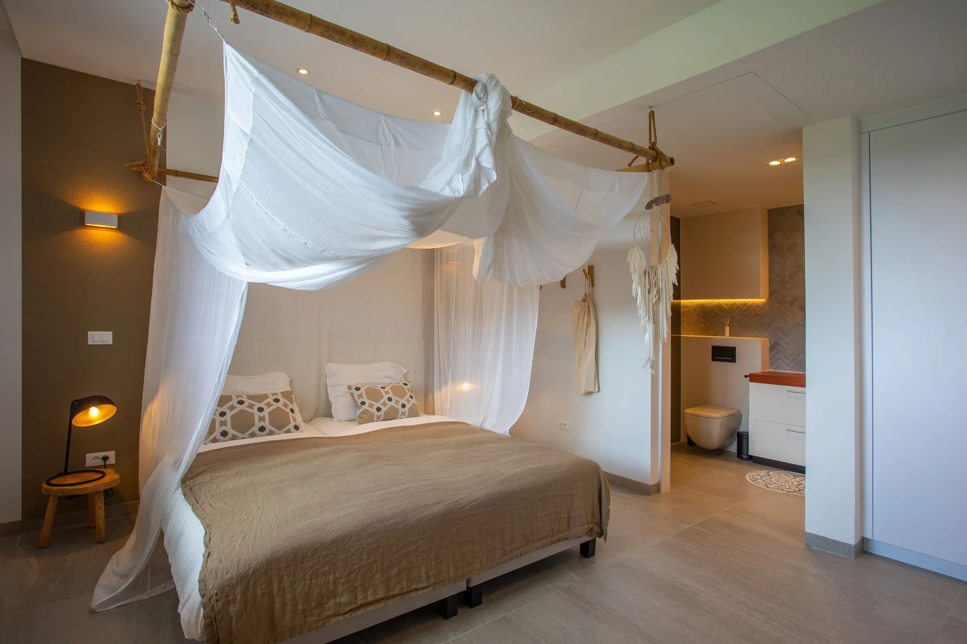 Canopy king bed with an open bathroom area at Blue Bay Curacao Golf & Beach Resort.