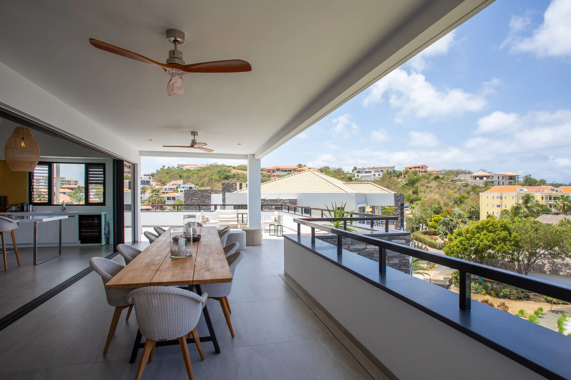 Covered penthouse terrace with dining table and hillside views at Blue Bay Curacao Golf & Beach Resort.