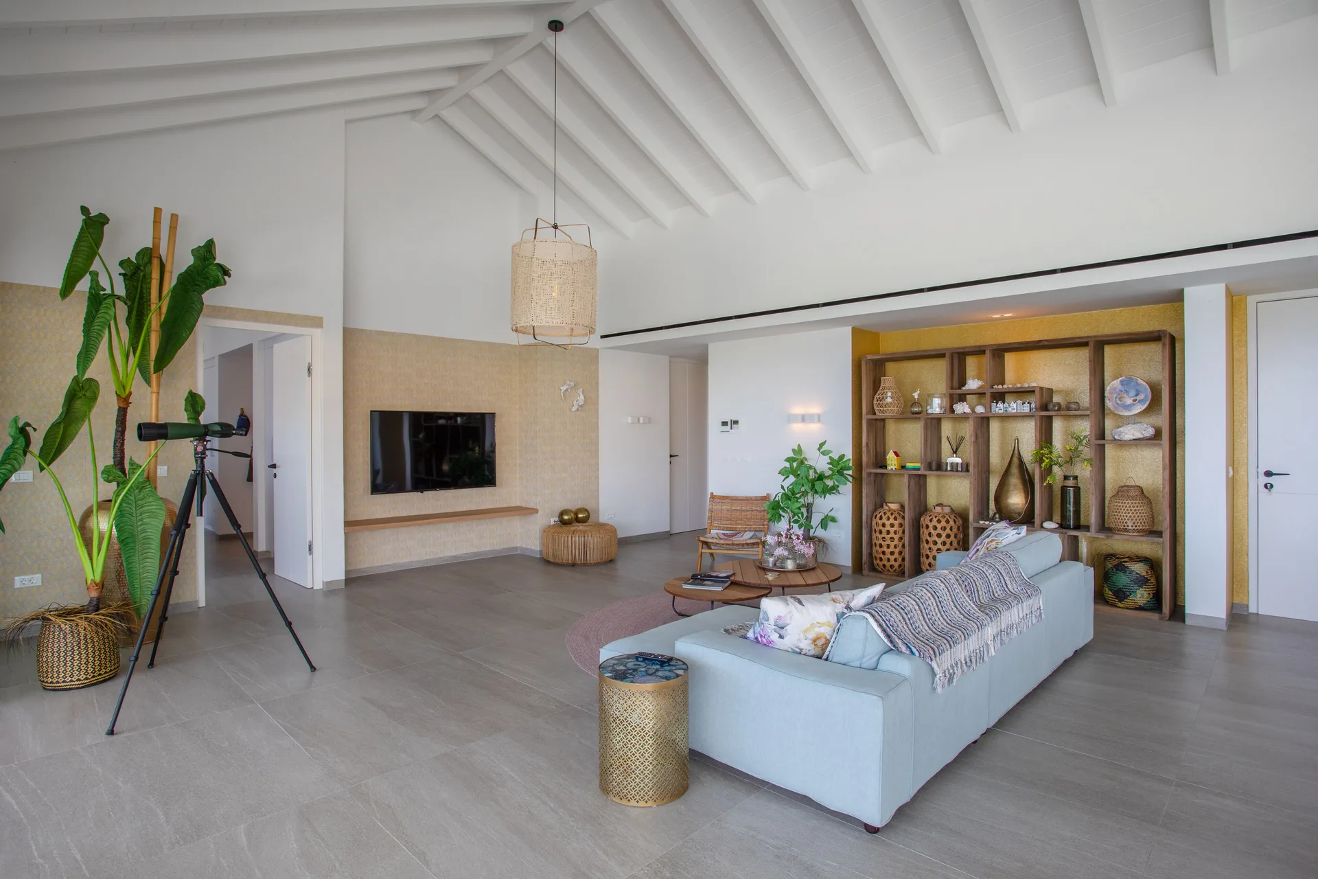Penthouse lounge with sofa, TV, shelving, and telescope at Blue Bay Curacao Golf & Beach Resort.