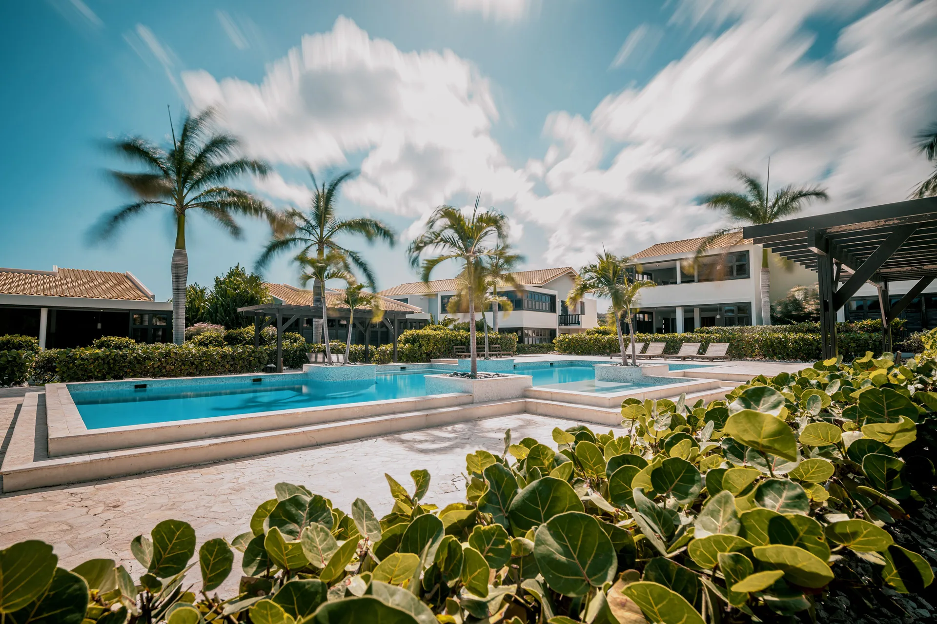 Garden Villa 2 Bedroom pool area at Blue Bay Curacao Golf & Beach Resort with palms, villas, and blue sky.