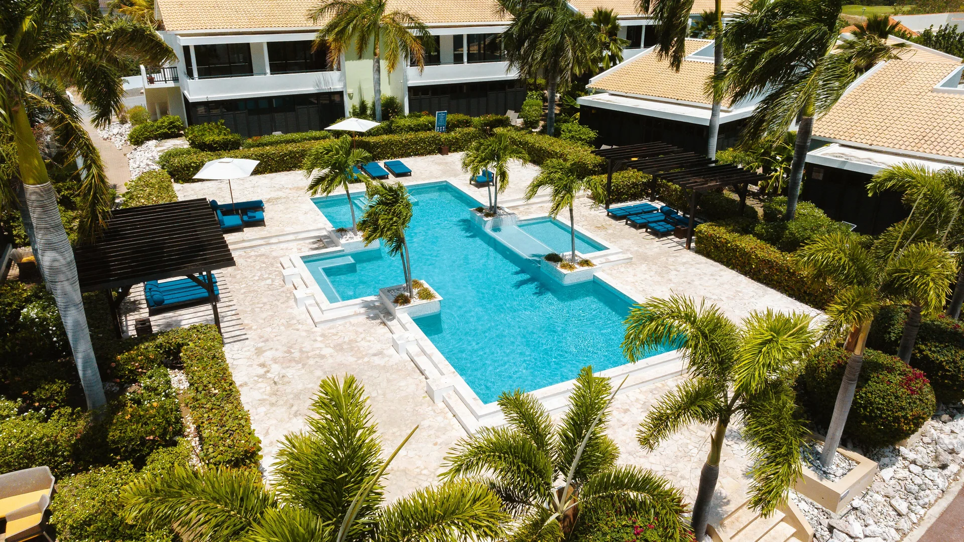 Garden Villa 2 Bedroom pool courtyard at Blue Bay Curacao Golf & Beach Resort with pergolas and palm trees.