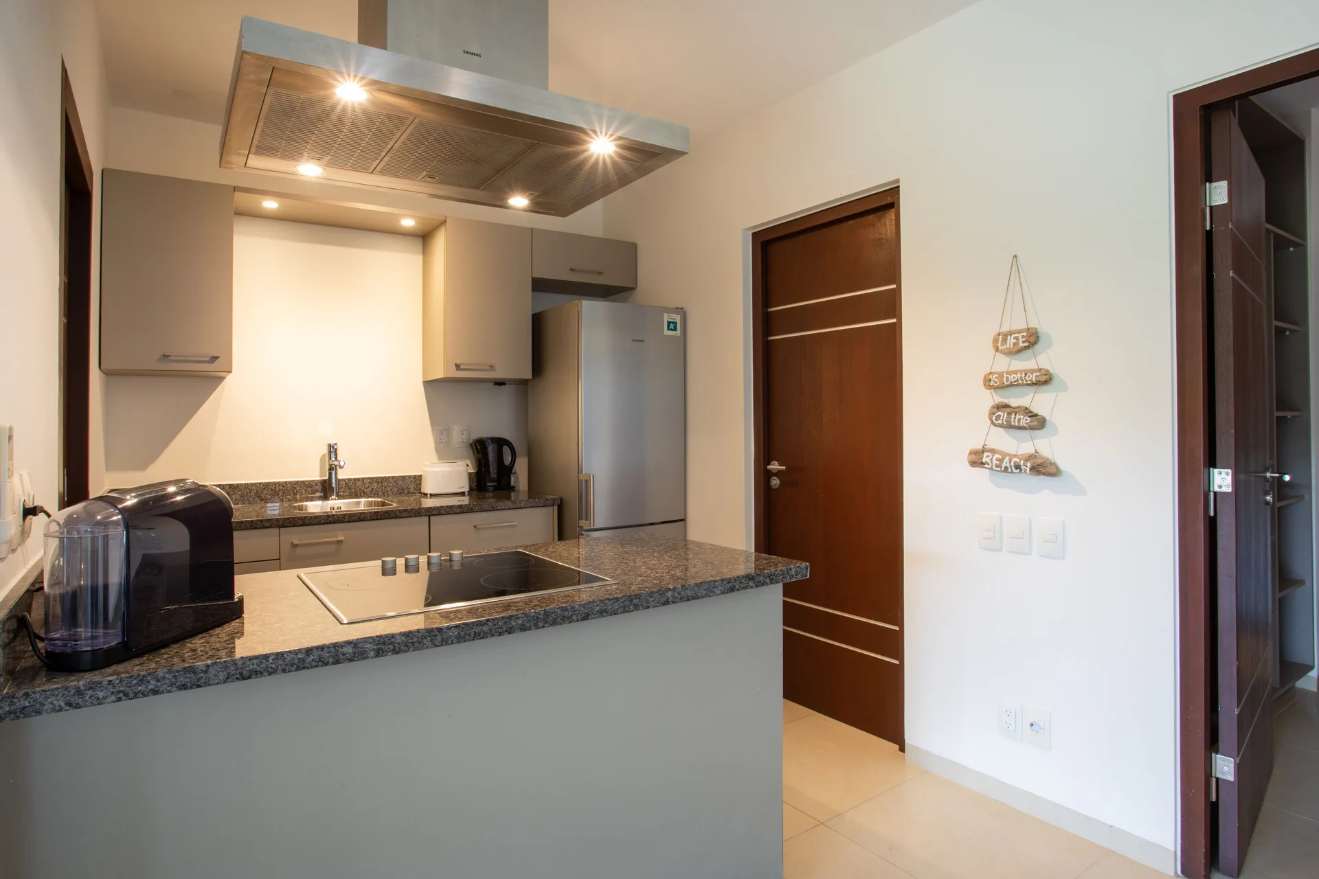 Kitchen in a Greenview apartment at Blue Bay Curacao Golf & Beach Resort with island cooktop and fridge.