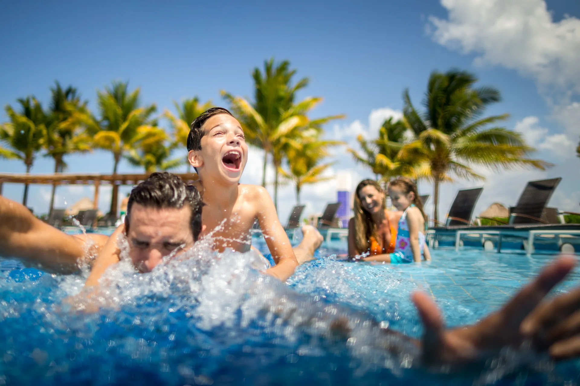 Family splashing together in the pool at BlueBay Grand Esmeralda.