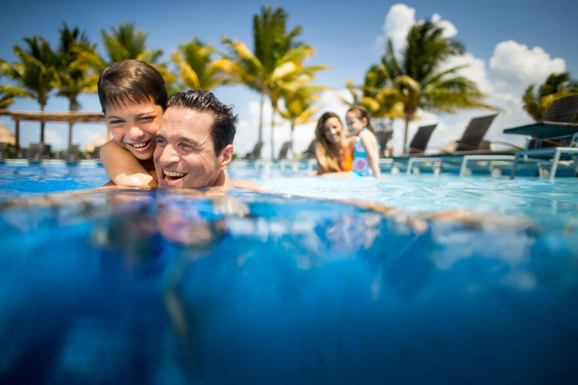 Family swimming in a sunny pool at BlueBay Grand Esmeralda.