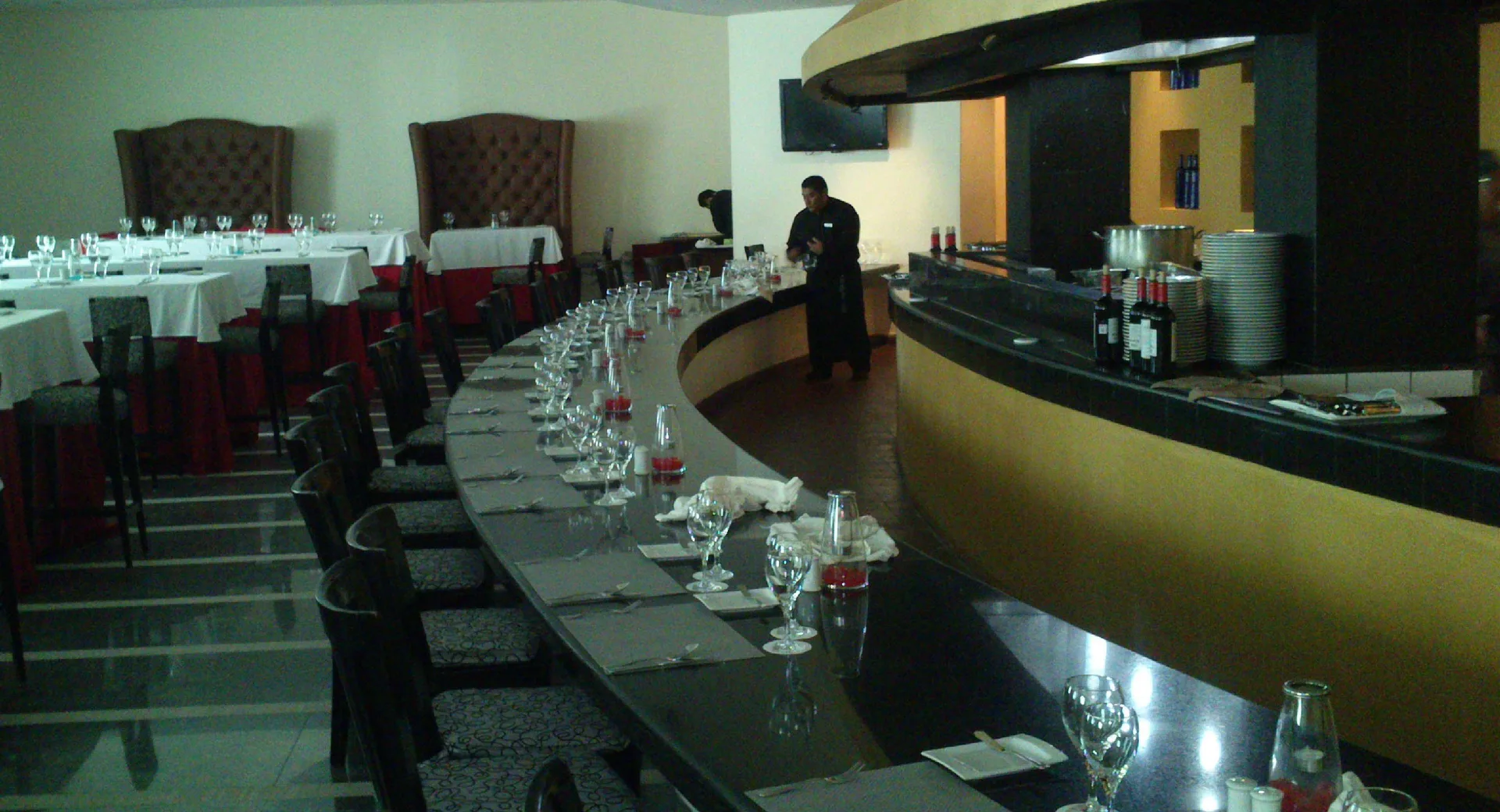 Steakhouse-style dining room with curved counter seating at BlueBay Grand Esmeralda.