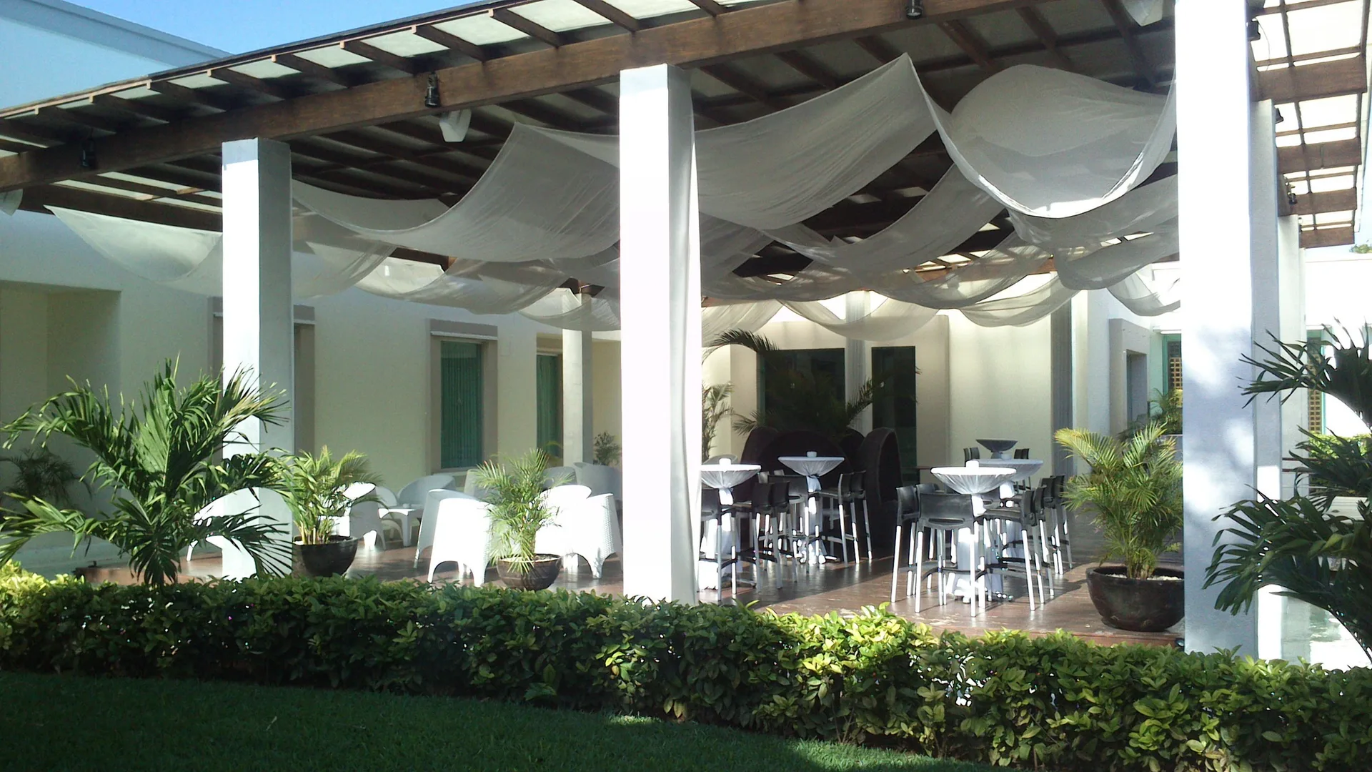 Open-air terrace with high tables and white draped ceiling at BlueBay Grand Esmeralda.