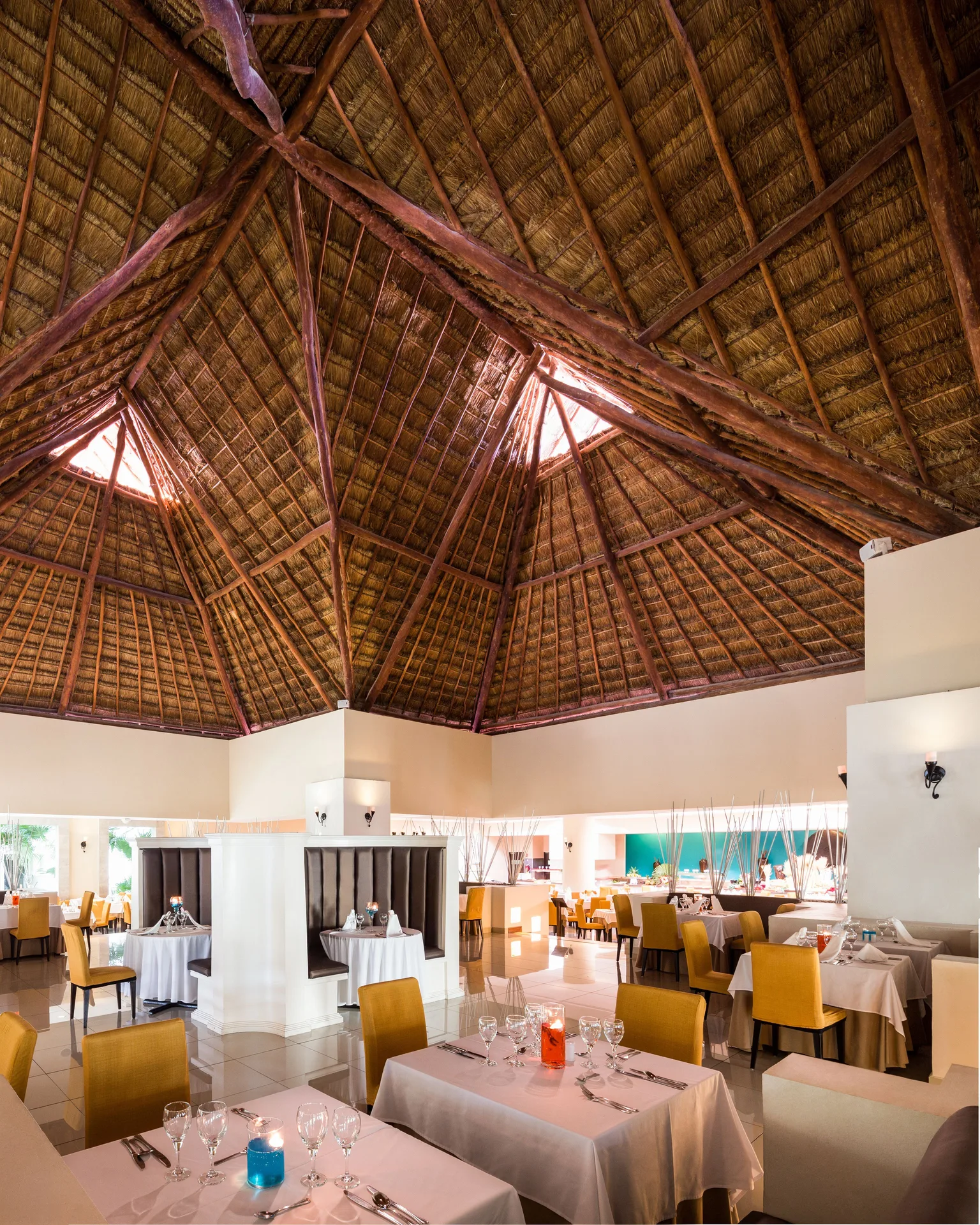 Elegant dining room with thatched ceiling and white table linens at BlueBay Grand Esmeralda.