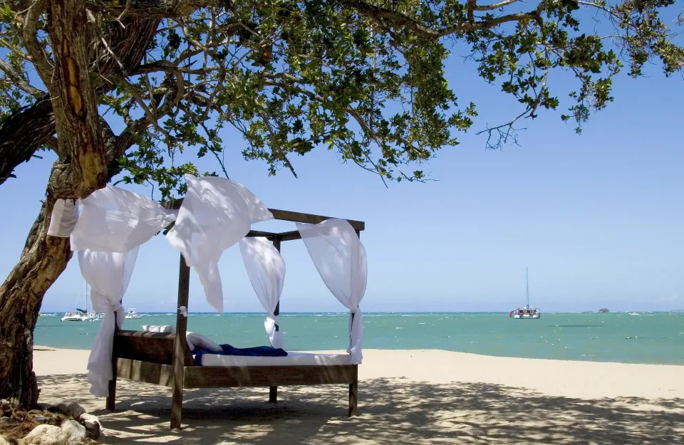 Shaded beach daybed with white curtains at BlueBay Villas Doradas.