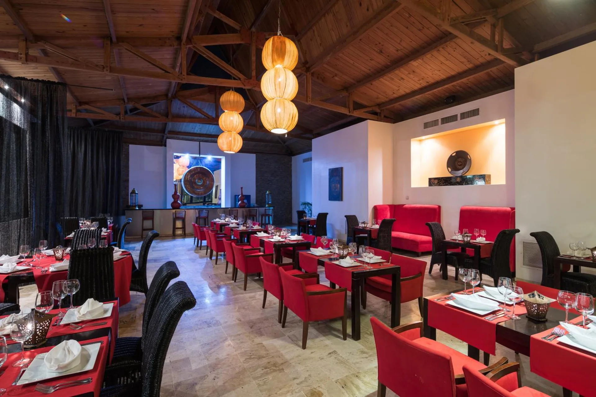 Asian-style restaurant dining room with red seating at BlueBay Villas Doradas.