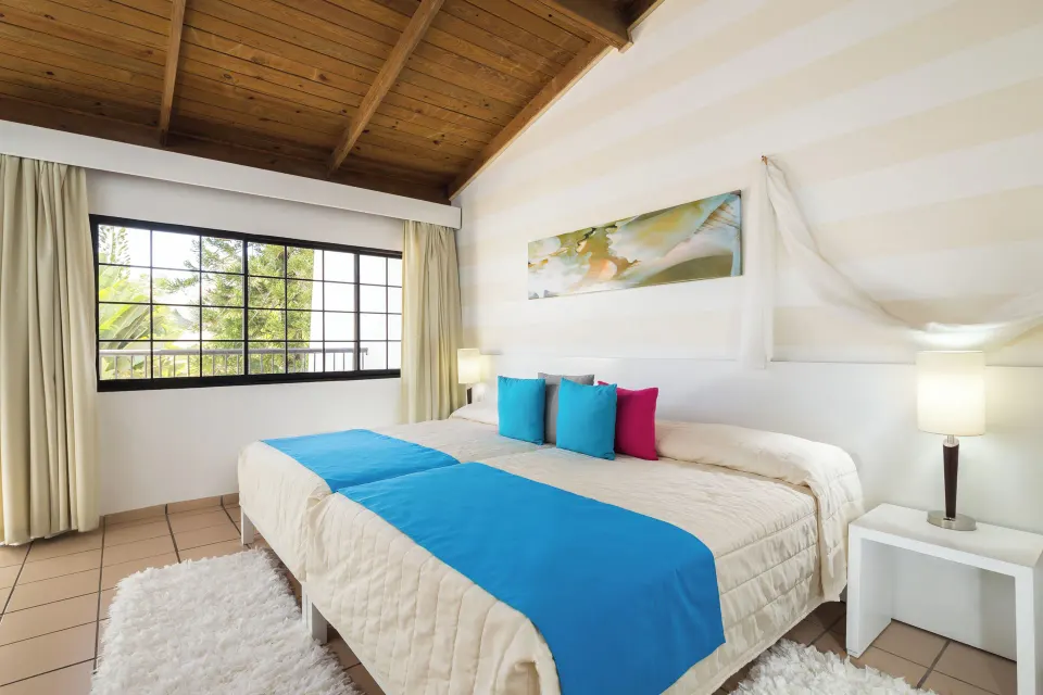 Standard Room with blue bed runner and large window at BlueBay Villas Doradas.