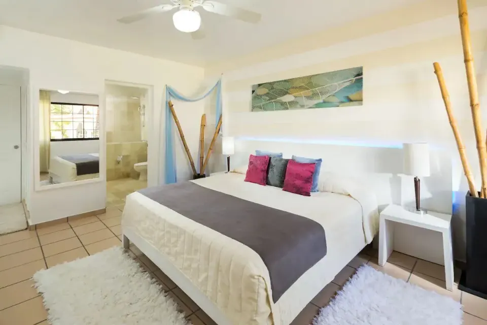 Standard Room with white bed and open bathroom at BlueBay Villas Doradas.