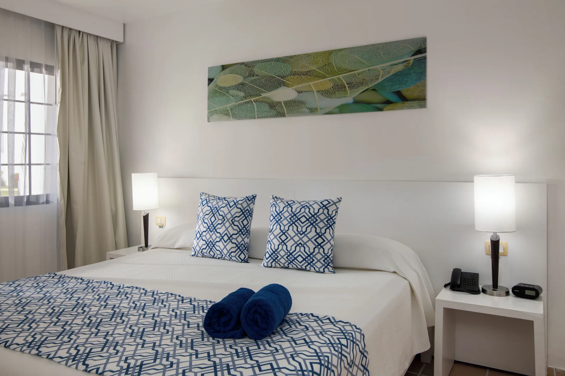Standard Room bed with patterned pillows and blue towels at BlueBay Villas Doradas.