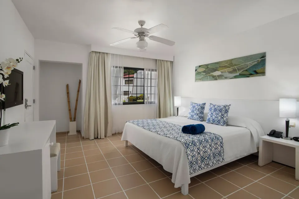 Standard Room with bed, TV, window, and tiled floor at BlueBay Villas Doradas.