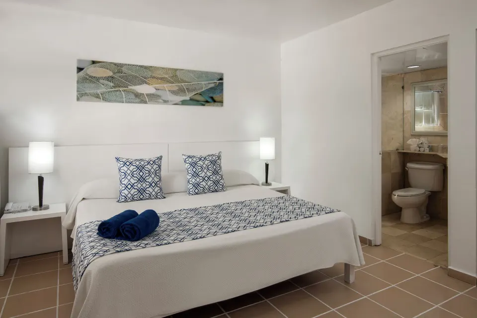 Superior Room king bed and bathroom at BlueBay Villas Doradas.