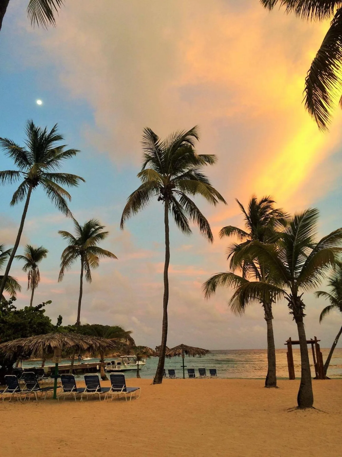 Beach chairs, palm trees and sunset clouds on the sand at Bolongo Bay Beach Resort.