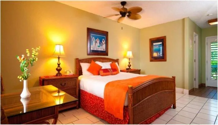 King bed guest room with glass-top table and balcony door at Bolongo Bay Beach Resort.