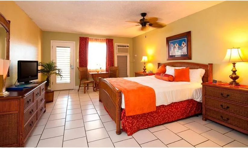 King bed guest room with dresser, TV, desk, and red curtains at Bolongo Bay Beach Resort.