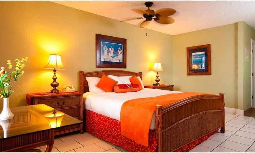 King bed guest room with wicker furniture and orange accents at Bolongo Bay Beach Resort.