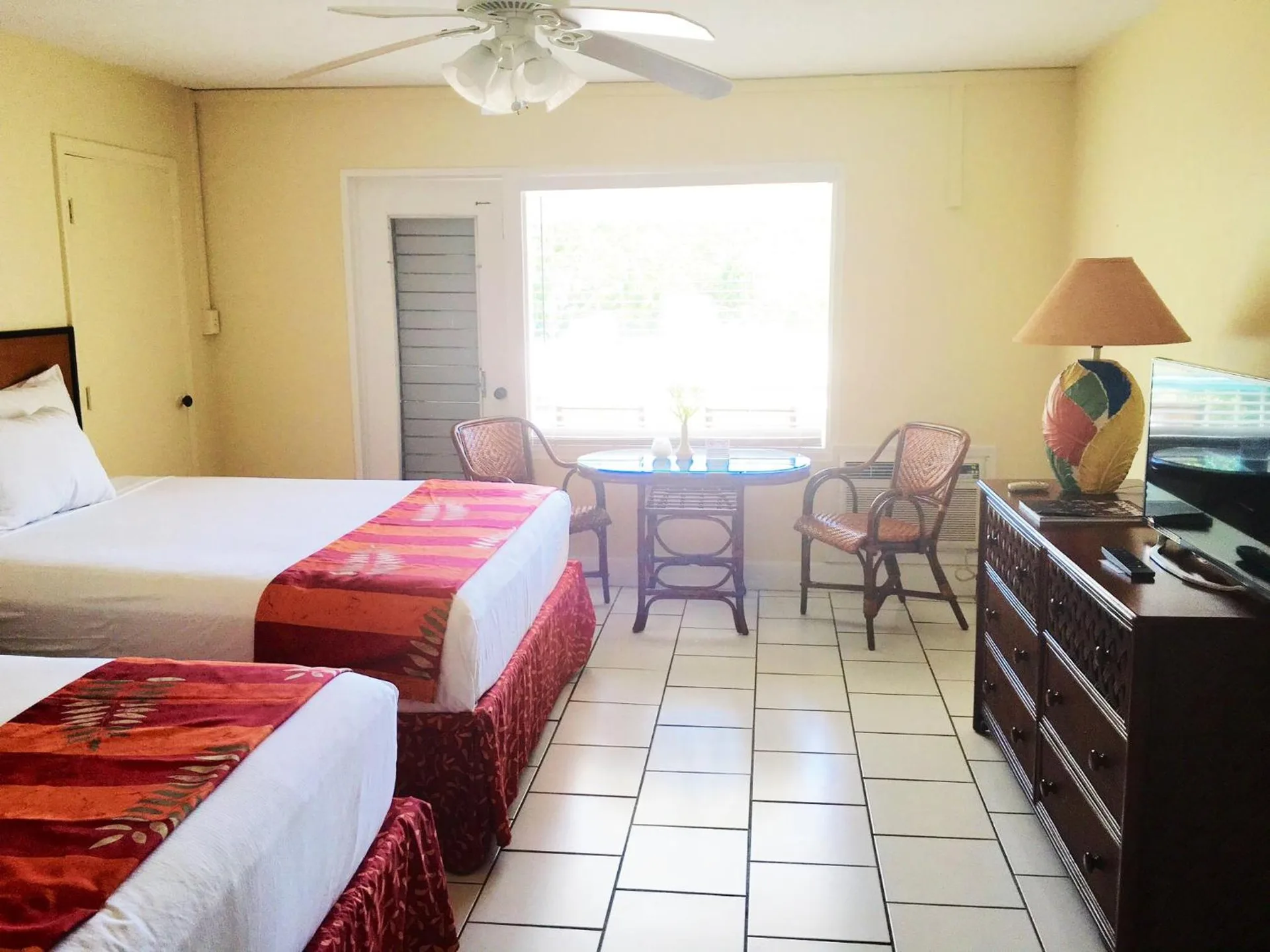 Guest room with two beds, wicker chairs and tile floor at Bolongo Bay Beach Resort.