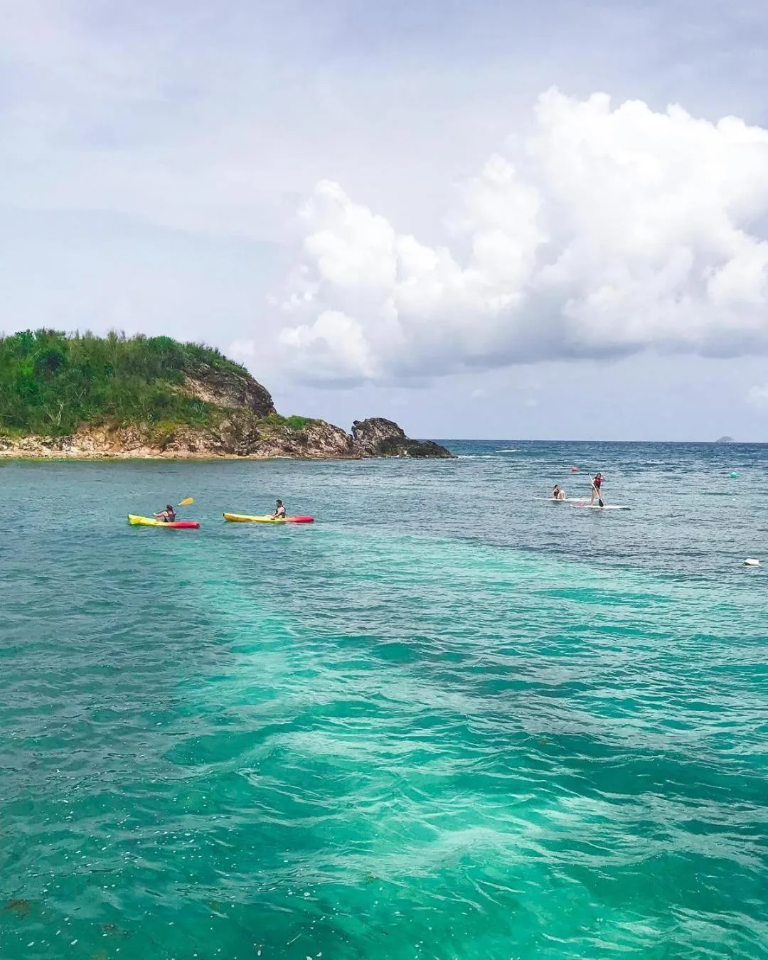 Kayakers and paddleboarders on turquoise water at Bolongo Bay Beach Resort.