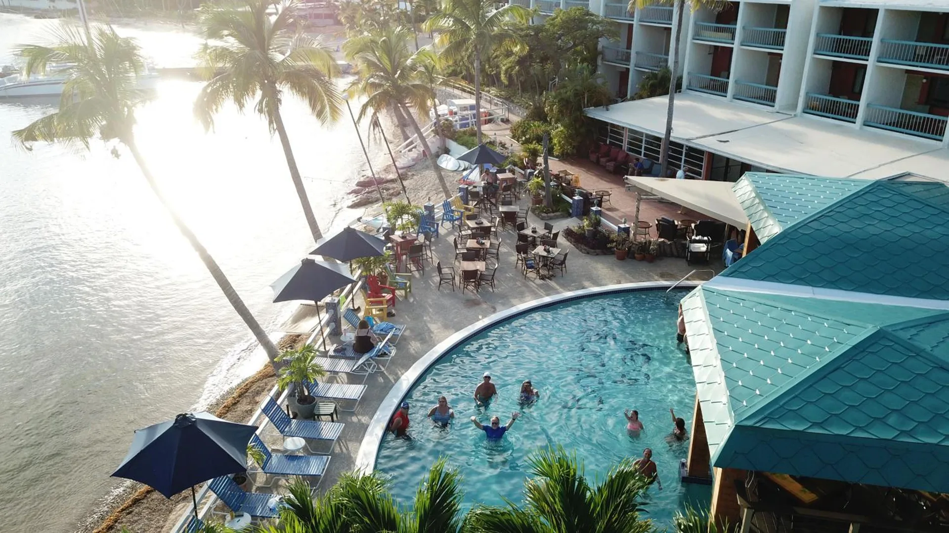 Pool, patio seating, palms, and bayfront buildings at Bolongo Bay Beach Resort.