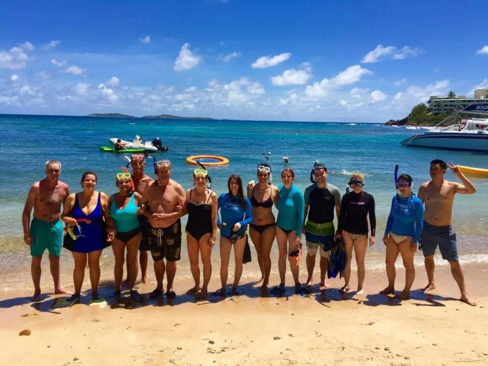 A snorkeling group stands on the beach beside turquoise water at Bolongo Bay Beach Resort.