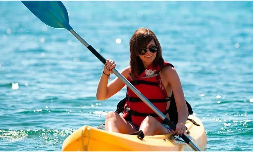 A guest paddles a yellow kayak on blue water at Bolongo Bay Beach Resort.