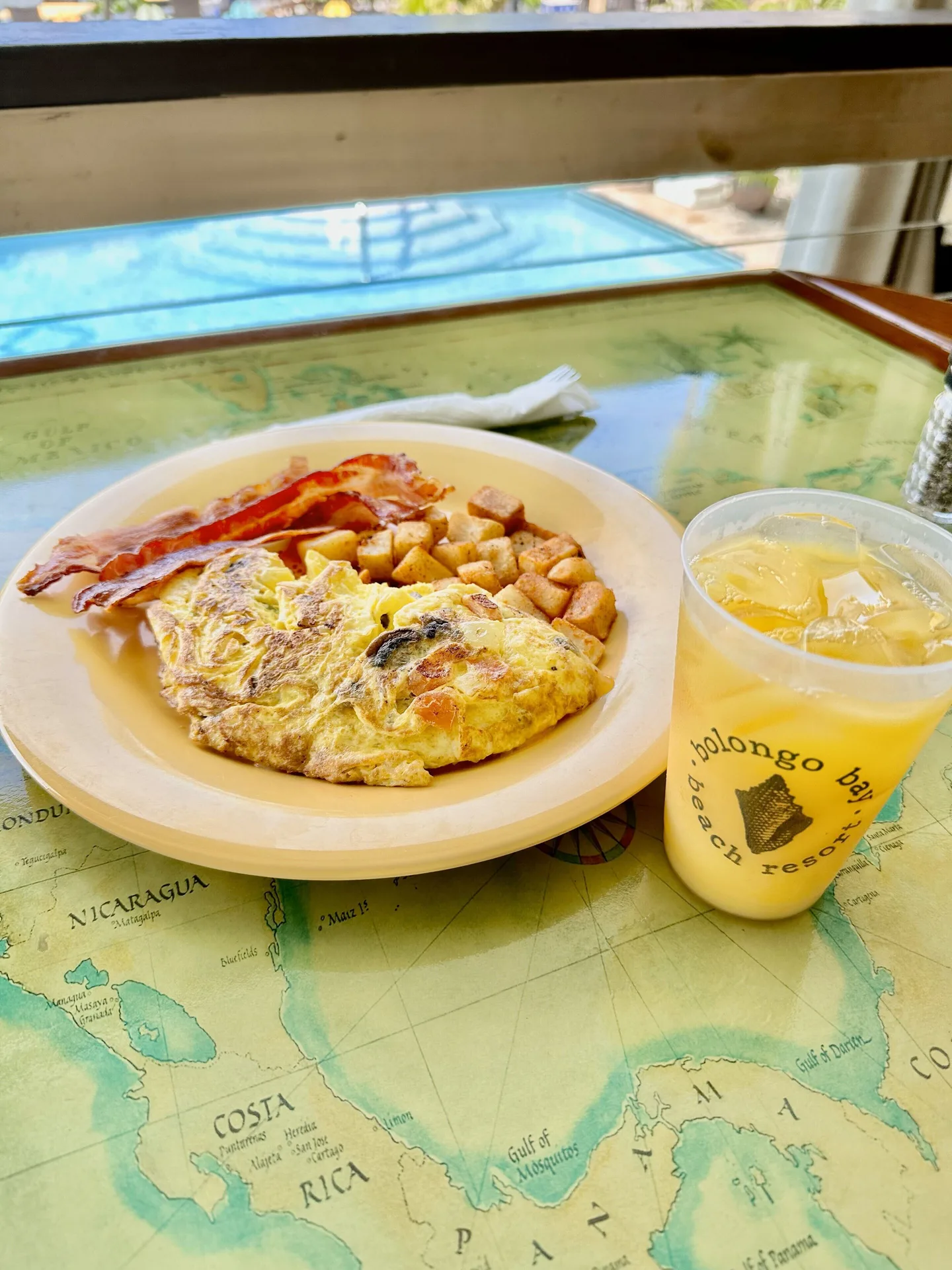 Omelet, bacon, potatoes, and juice on a map table at Bolongo Bay Beach Resort.