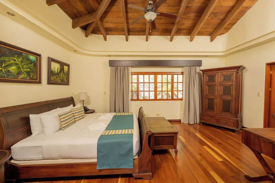Junior Suite king bed, armoire, and window at Borinquen Thermal Resort.