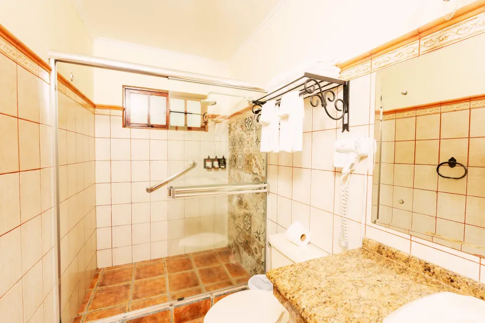 Standard Bungalow bathroom with glass shower and vanity at Borinquen Thermal Resort.
