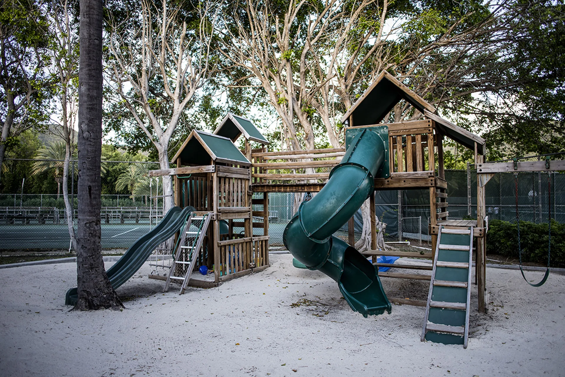 Wooden playground with green slides and swings at Carlisle Bay.