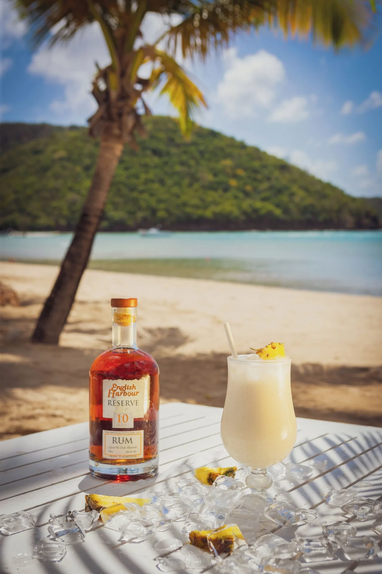 Tropical rum bottle and creamy cocktail on a beach table at Carlisle Bay.
