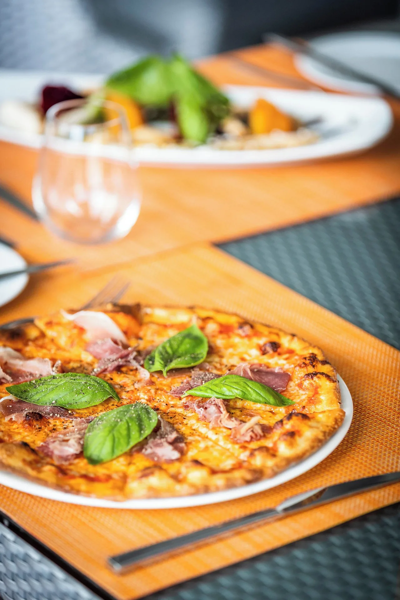 Thin-crust pizza with basil on an outdoor table at Carlisle Bay.