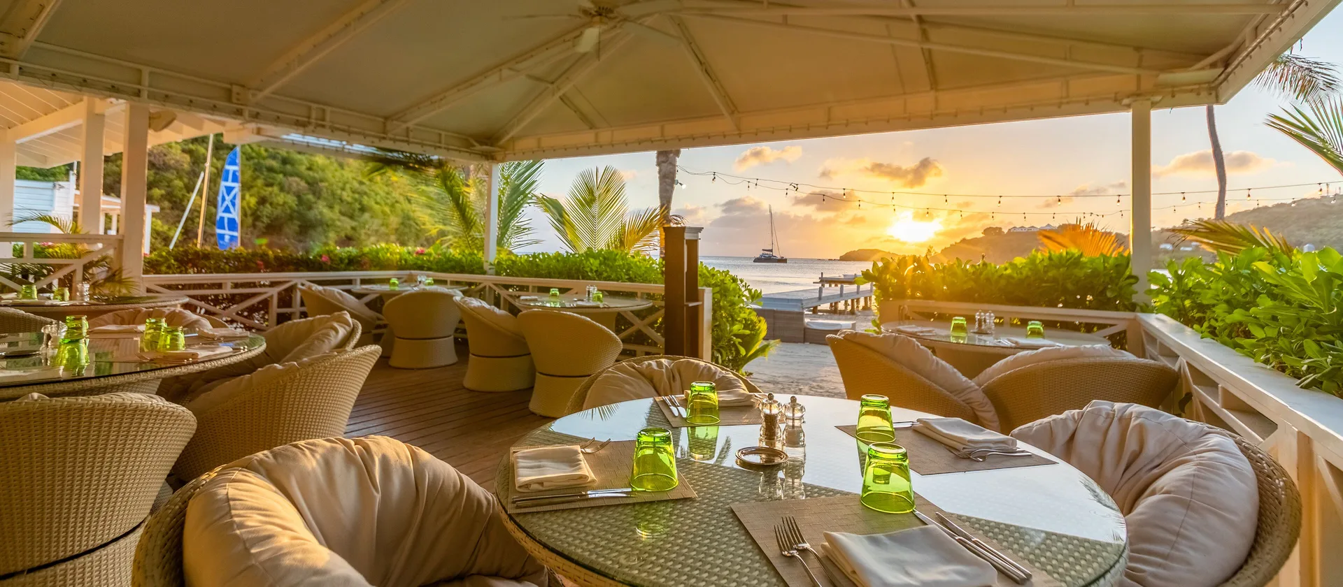 Terrace dining tables set for sunset over the water at Carlisle Bay.
