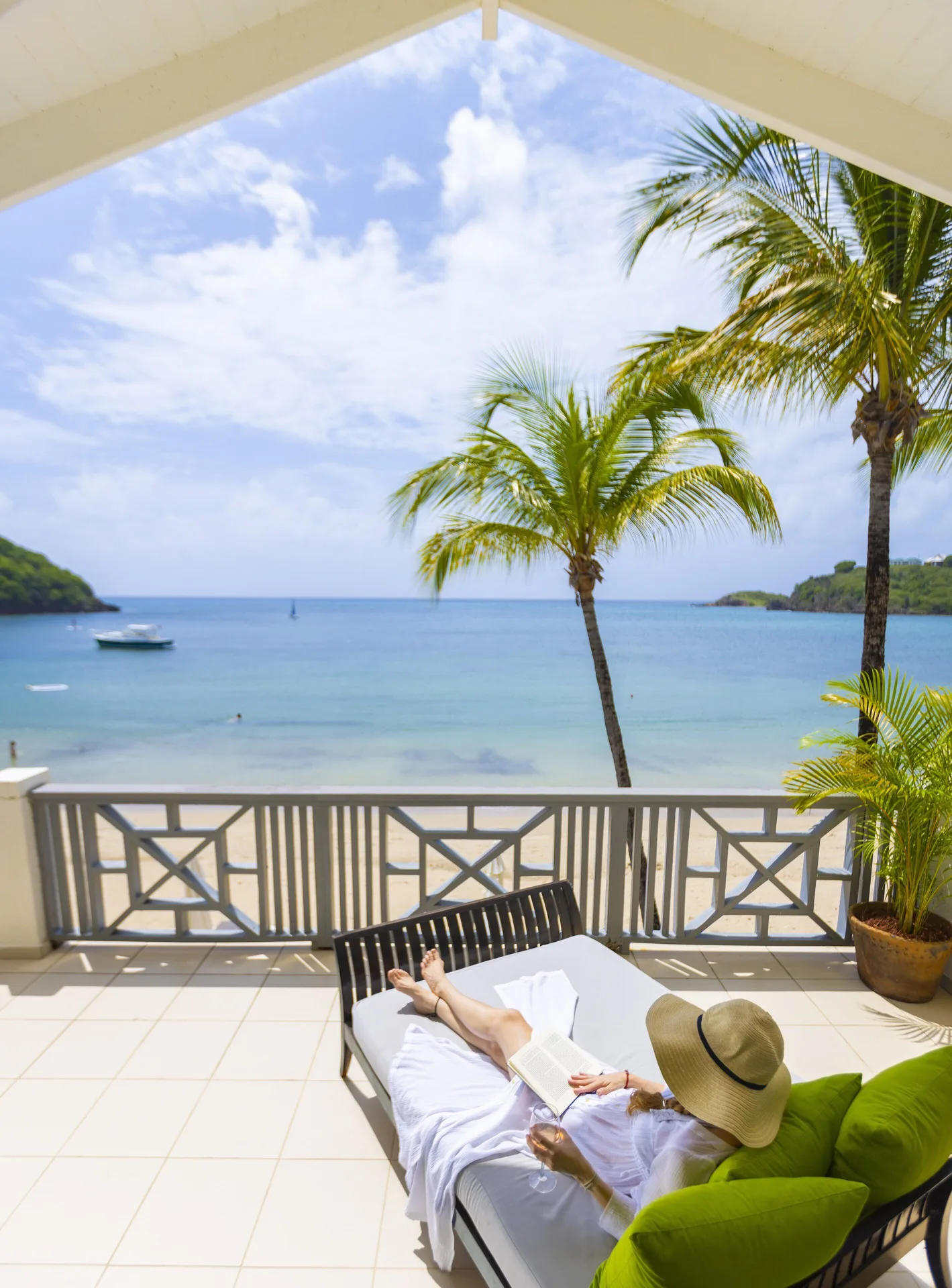 Beach balcony suite terrace at Carlisle Bay with a lounger overlooking palm trees and the bay.
