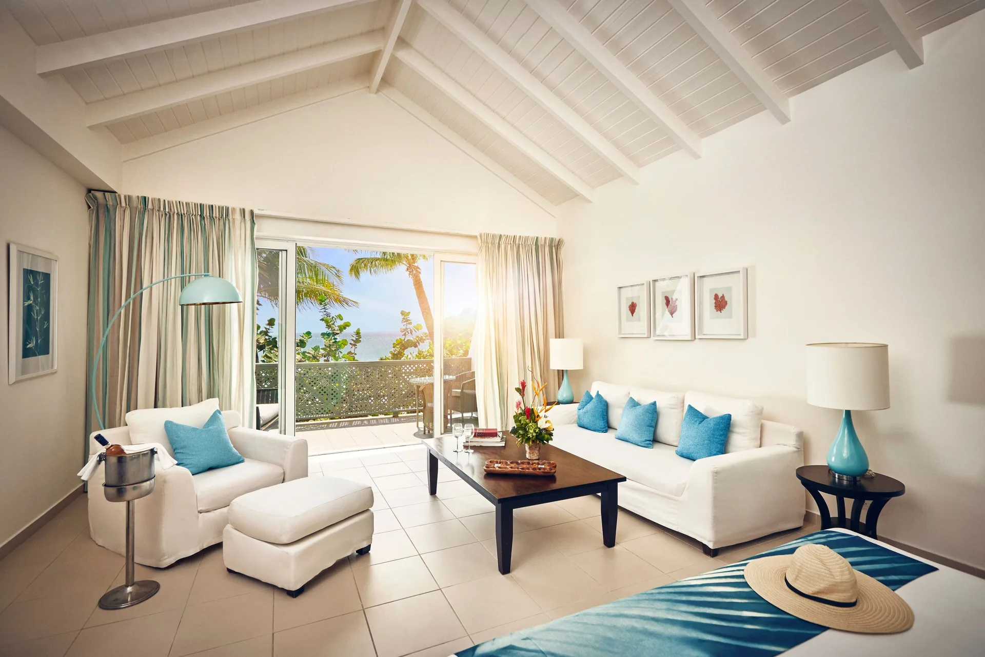 Beach balcony suite living area at Carlisle Bay with white seating, vaulted ceiling and balcony doors.