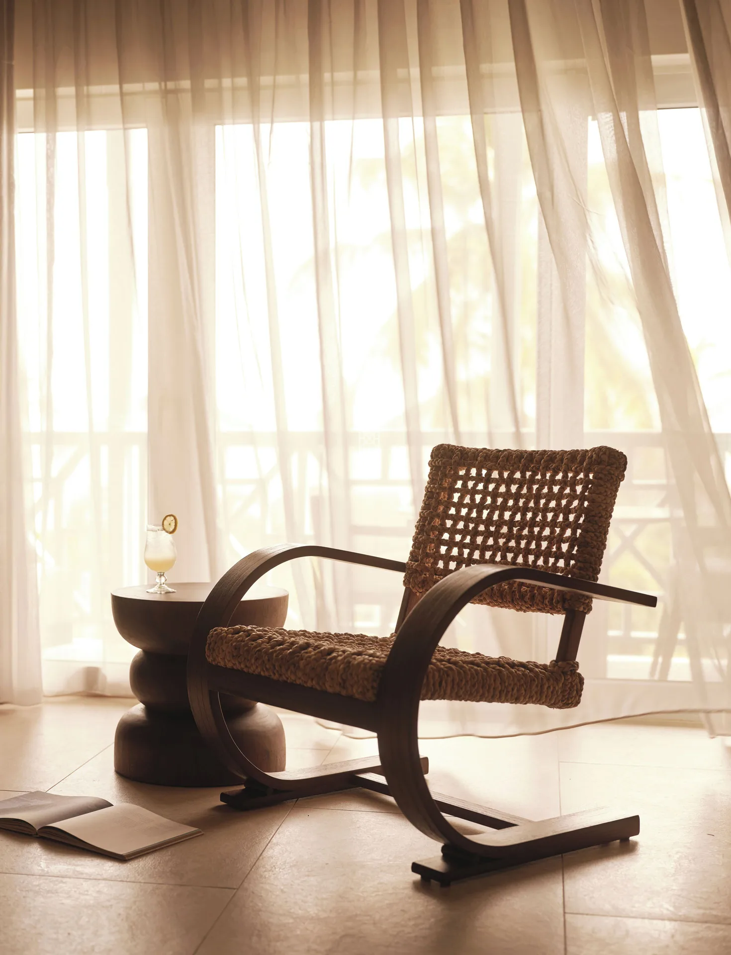 Ocean Suite woven lounge chair beside sheer balcony curtains at Carlisle Bay.