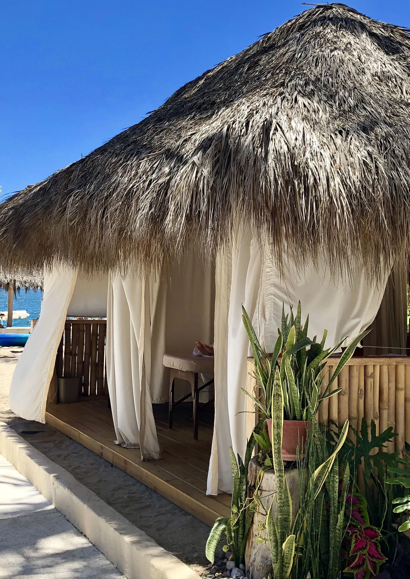 Thatched beach cabana with white curtains at Club Regina Puerto Vallarta.